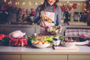 mulher cozinhando ceia de natal com itens comumente presentes em uma cesta de natal para empresas