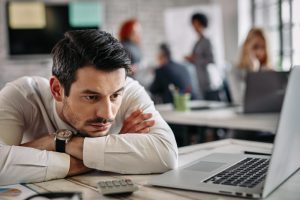 Homem recostado à mesa de trabalho com expressão desmotivada expressando quiet quitting