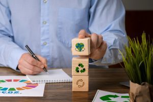 Três blocos de madeira sobre uma mesa com símbolos de sustentabilidade mostram como atrelar o ajuste do vale-refeição aos conceitos de sustentabilidade
