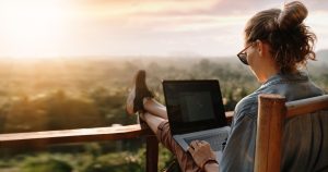 Mulher pratica o anywhere office na varanda com vista para a planície