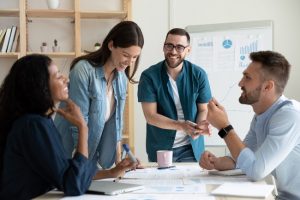 grupo de colaboradores conversam sorridentes em reunião de negócios