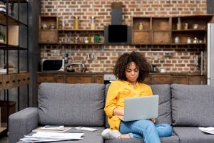 mulher jovem trabalhando do sofá da sua casa