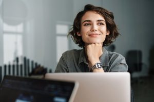 mulher sorridente olhando para o horizonte com notebook