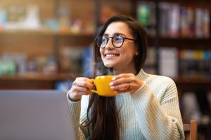 Funcionária feliz sorri no trabalho enquanto toma um café