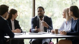 Liderança de um time de colaboradores falando com seu time durante uma reunião