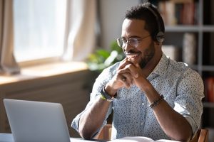 homem com headset estudando com benefício flexível em frente ao notebook