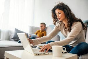 mulher trabalhando em seu computador perto do seu filho