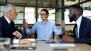 Mulher líder resolvendo um conflito entre dois colaboradores no trabalho