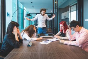 Reunião estressante no trabalho onde um dos membros está em pé gritando