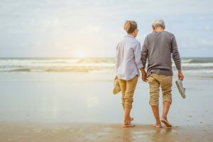 casal aposentado andando pela praia