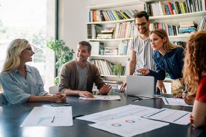 funcionários felizes discutem gráficos de resultados ao redor de mesa