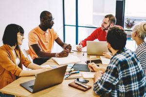 pessoas conversam ao redor de mesa com gestor ao meio