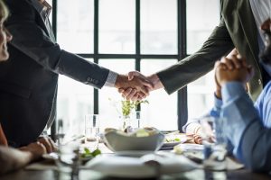 duas pessoas apertando as mãos num almoço de negócios