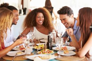 grupo de pessoas diversas comendo em restaurante