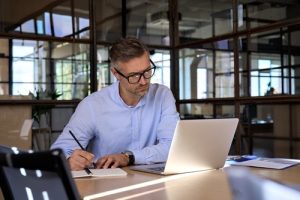 Homem de negócios pesquisando modelos de organogramas na Internet e fazendo anotações