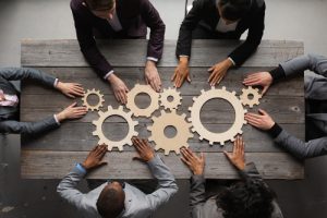 Planejamento-empresarial-sendo-realizado-em-uma-mesa-de-reunioes-utilizando-engrenagens-visto-do-alt