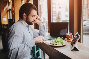 homem almoçando falando ao telefone