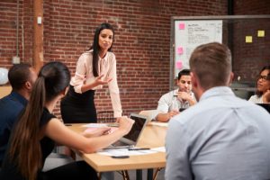 mulher líder promovendo troca de informações em reunião com outros colaboradores