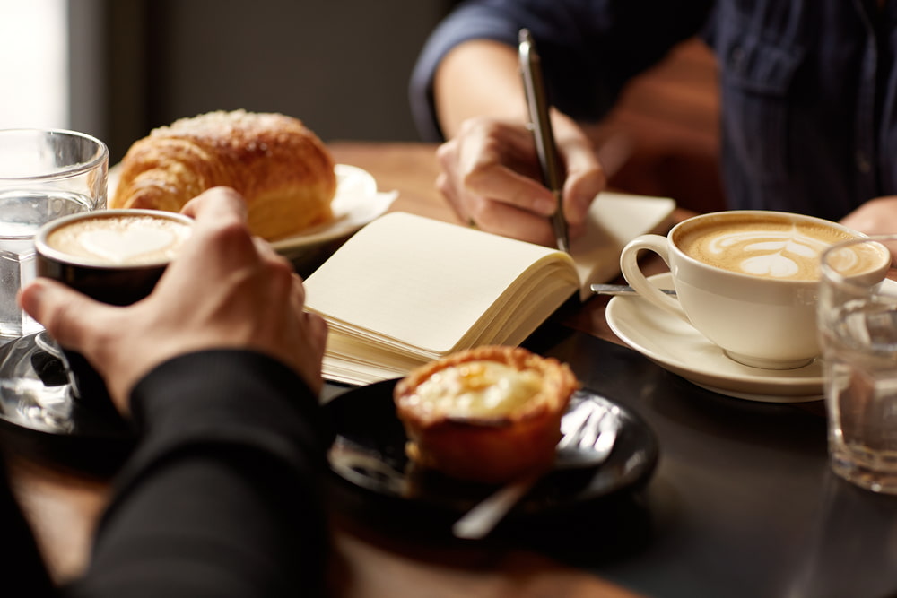 duas pessoas fazendo uma reunião tomando café