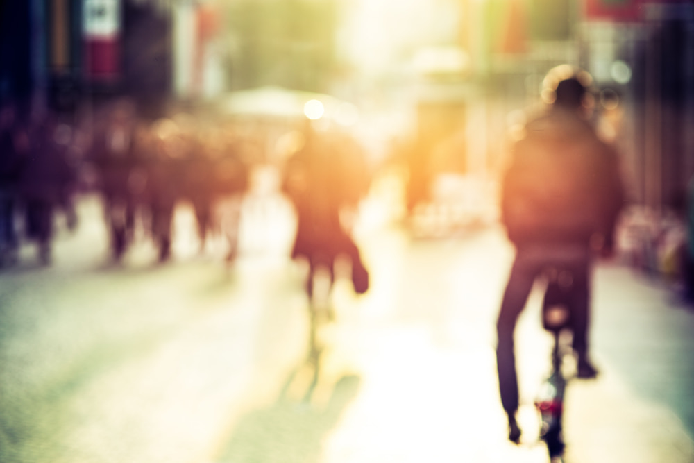 Visão desfocada de uma cidade futura com pessoas nas ruas e um ciclista
