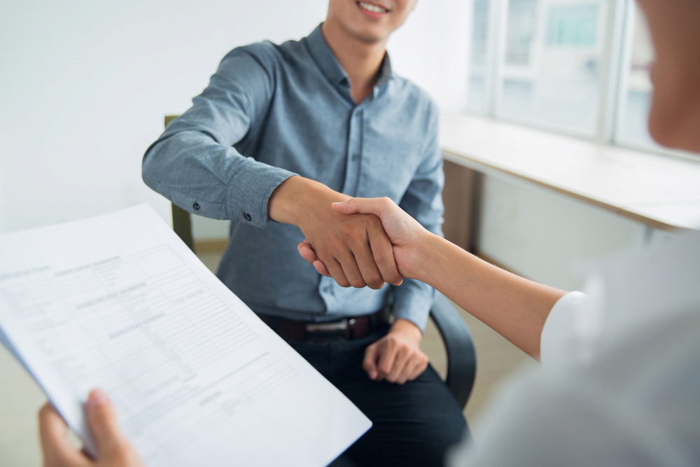 dois colegas de trabalho apertam as mãos