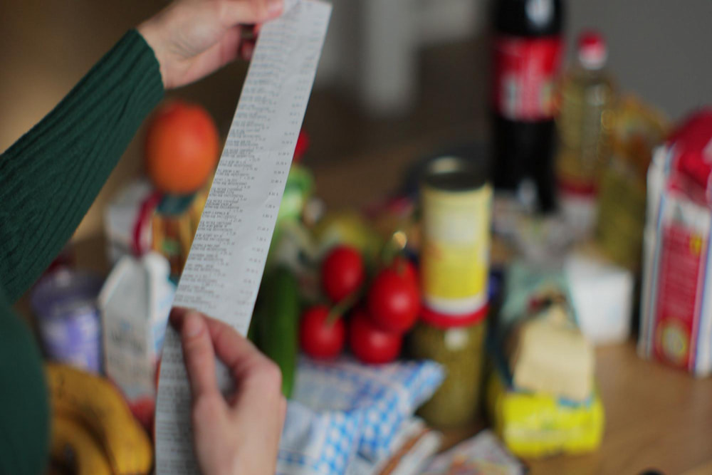 Mulher analisa tíquete de compras que fez com vale-alimentação