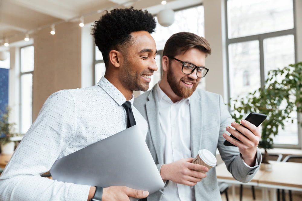 dois homens sorridentes olham para um smartphone