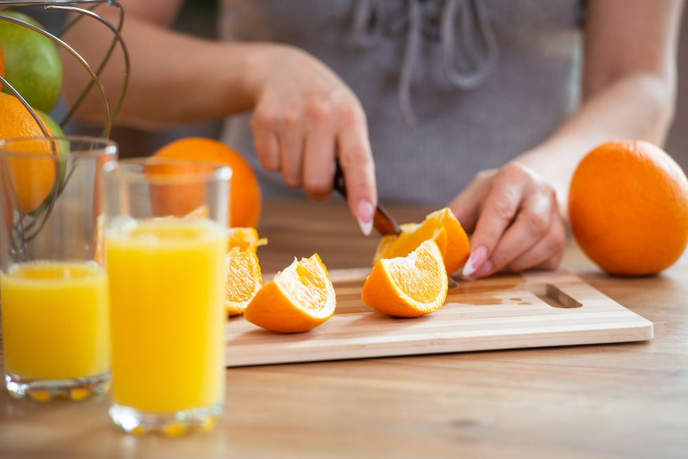 Imagem de uma mulher cortando laranjas