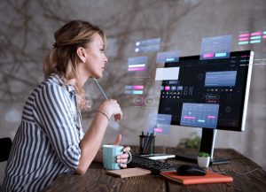 mulher sentada observa tela do seu computador com efeitos visuais que simulam realidade aumentada