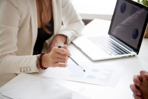 mulher sentada atua em um dos pilares da gestão empresarial conferindo gráficos financeiros