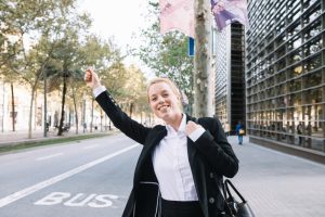 Mulher em pé na rua da sinal para o ônibus aproveitando a short friday oferecida pela empresa