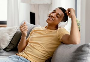 Homem sentado no sofá de sua casa com fone de ouvido aproveitando a short friday