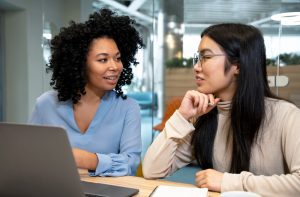 Duas mulheres sentadas à mesa do escritório praticando mentoria