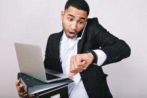 Homem segurando notebook enquanto olha para o relógio