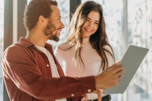 Homem mostra um papel animadamente para uma mulher, que sorri