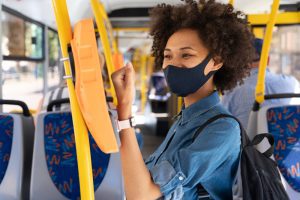 Mulher de máscara passa pela catraca do ônibus simbolizando benefícios obrigatórios
