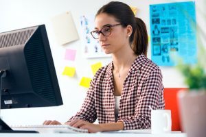 Mulher sentada em frente ao computador trabalha na implementação da matriz de competências