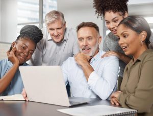 Cinco colaboradores de diferentes idades e raças trabalham juntos animadamente