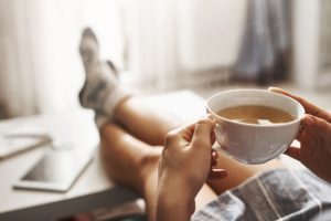 Pessoa com pés na mesa de centro e uma xícara de chá descansa na semana de 4 dias de trabalho