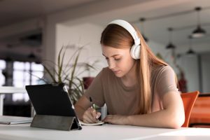 mulher sentada com fone de ouvido assiste ao tablet