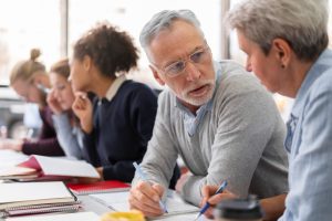Mesa de trabalho compartilhada por cinco pessoas que trabalham e conversam