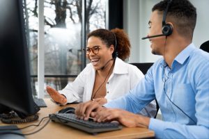 Duas pessoas sentadas à mesa com headsets trabalham animadamente na semana de 4 dias de trabalho