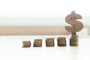 Cinco pilhas de moedas em tamanhos diferentes e um cifrão na maior