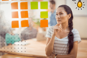 Mulher asiática em frente a painel de vidro com post-its coloridos analisa sua matriz de competências