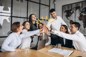 Homens e mulheres em sala de reunião batem as mãos animadamente