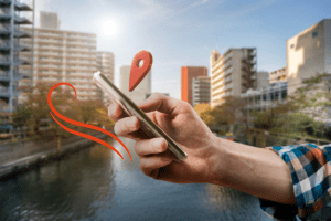 Mão masculina segurando celular com pin de geolocalização vermelho