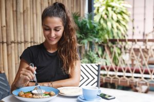 Mulher toma café e come sentada à mesa
