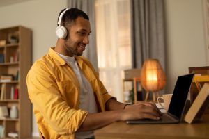 Homem com fone de ouvido sentado à mesa com laptop