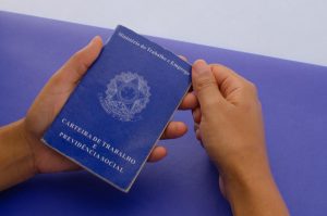 Mãos masculinas seguram carteira de trabalho em base azul