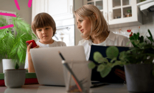 Mulher trabalha em home office ao lado de filho